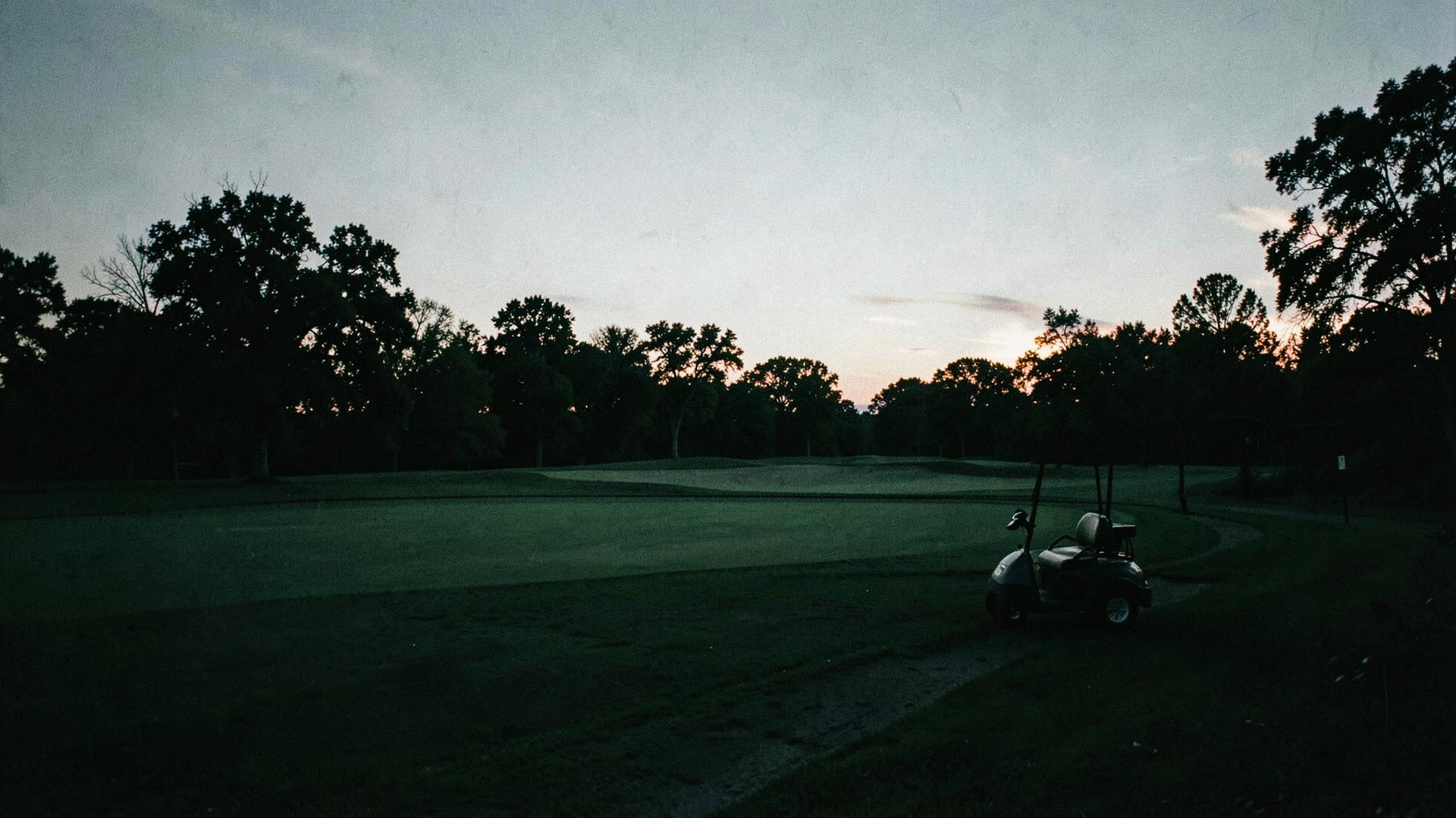 Golf cart beside a fairway at dusk